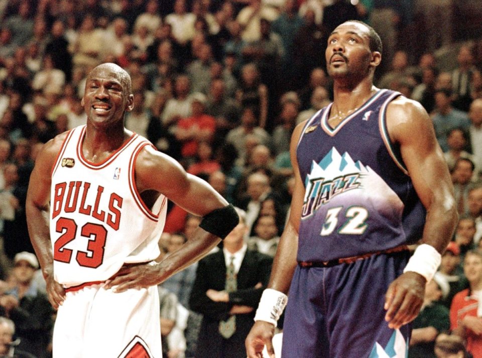 Michael Jordan (L) sonríe durante un tiro libre junto a Karl Malone (R) en las Finales de la NBA en 1998.