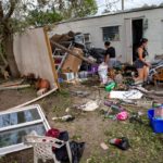 Residentes de una casa móvil en Fort Myers, Florida, examinan los daños provocados por el huracán Ian.