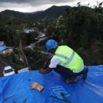 Personal coloca un toldo azul sobre el techo de una casa afectada por el huracán María en Morovis, Puerto Rico.