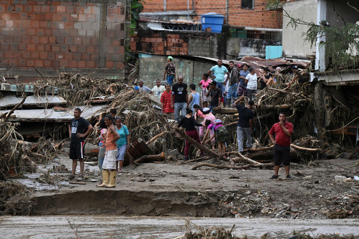 Residents remain among the rubble of destroyed houses washed away by a landslide during heavy rains in Las Tejerias, Aragua state, Venezuela, on October 9, 2022. - A landslide in central Venezuela left at least 22 people dead and more than 50 missing after heavy rains caused a river to overflow, Vice President Delcy Rodriguez said Sunday. (Photo by Yuri CORTEZ / AFP) (Photo by YURI CORTEZ/AFP via Getty Images)