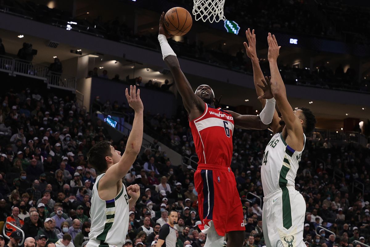 Montrezl Harrell (C) consigue una cesta ante la defensa de Giannis Antetokounmpo (R).