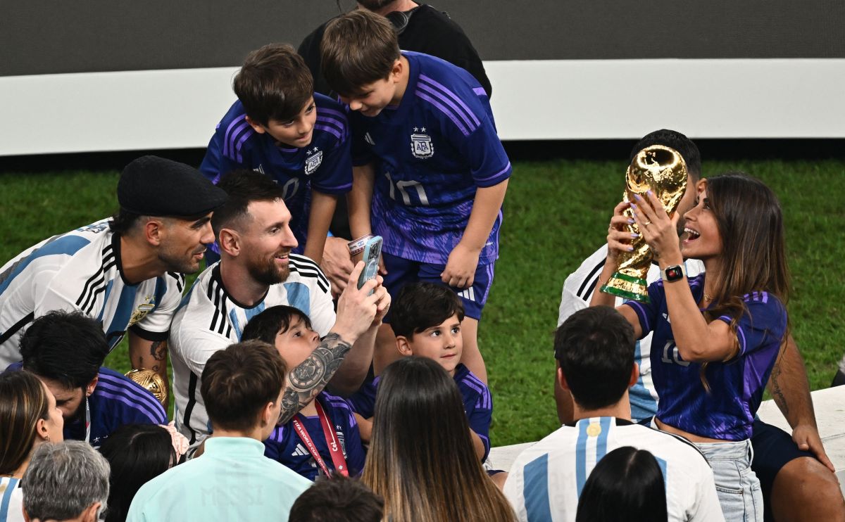 Antonela Roccuzzo (R) posa con la Copa del Mundo mientras su pareja, Lionel Messi, le toma una foto. 