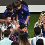 Antonela Roccuzzo (R) posa con la Copa del Mundo mientras su pareja, Lionel Messi, le toma una foto.