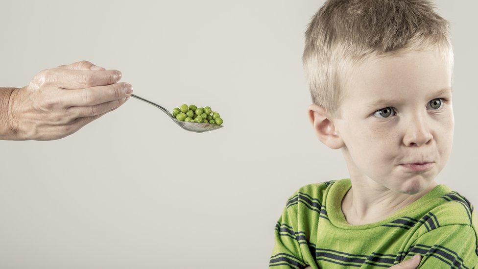 Niño al que le ofrecen una cuchara con comda