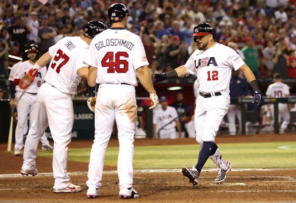 Kyle Schwarber (R) es felicitado por Paul Goldschmidt y Mike Trout luego de conectar jonrón ante Gran Bretaña.