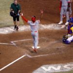 Otto López pisa el plato luego de disparar un cuadrangular ante la mirada del catcher colombiano Elías Díaz.