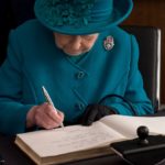 La reina Isabel II escribiendo una carta.