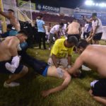 Fanáticos auxilian a personas durante una estampida en el Estadio Cuscatlán del Salvador.